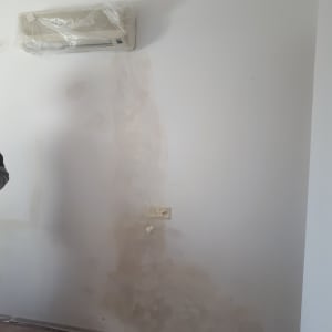 קיר צבוע חלקית עם תיקוני טיח ופלסטיק על המזגן