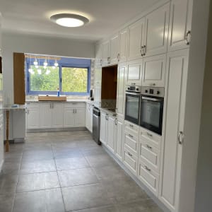 מטבח מודרני עם ארונות לבנים ותנורים מובנים