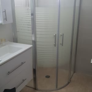 מקלחון זכוכית עם דלתות מתכת בחדר אמבטיה