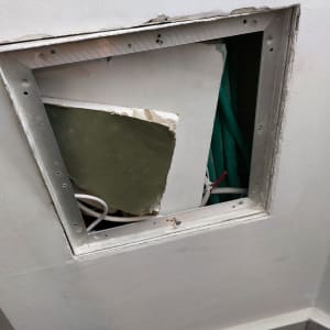 פתח בקיר גבס עם חוטים ירוקים ולבנים