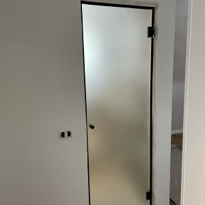 דלת זכוכית חלבית עם ידית מתכת בשירותים