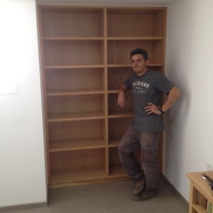 נגר עומד ליד מדף עץ גדול וריק