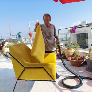 אדם מנקה ספה צהובה עם שואב אבק