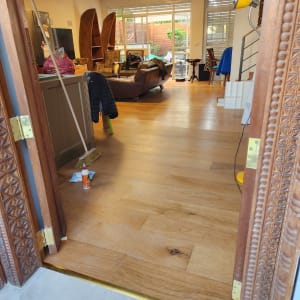 רצפת פרקט עץ עם דבק ומטאטא ליד הדלת