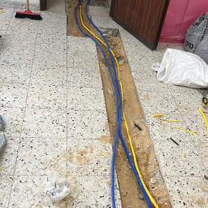 כבלים כחולים וצהובים מונחים בתעלה ברצפה