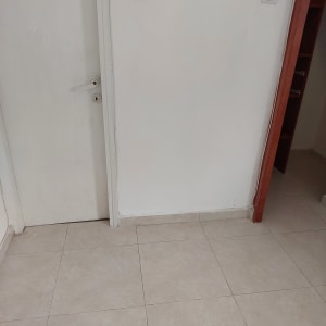 קיר צבוע בלבן עם דלת לבנה ורצפת אריחים