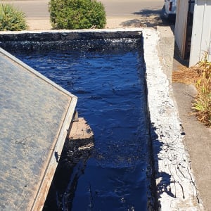 גג אטום בזפת שחורה עם לבנים לתמיכה