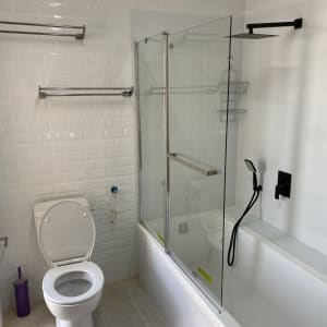 חדר אמבטיה עם אריחים לבנים, מקלחון זכוכית וברז שחור