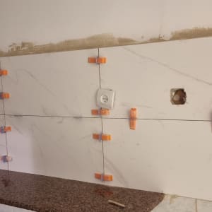 קיר עם אריחים מותקנים, קליפסים כתומים, חור לשקע חשמל