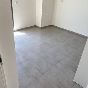 רצפת אריחים אפורה בחדר ריק עם קירות לבנים