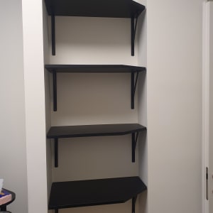 מדפים שחורים מותקנים על קיר עם תומכים מתכתיים