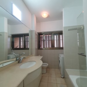 חדר אמבטיה עם כיור, ברז ומכונת כביסה