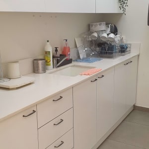 מטבח עם ארונות לבנים, כיור וכלי ניקוי