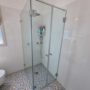 מקלחון זכוכית עם ראש מקלחת ומדף מוצרים