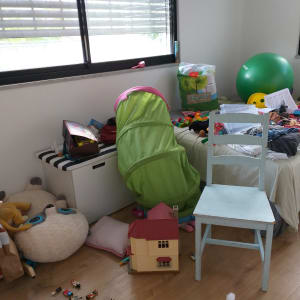 חדר מבולגן עם צעצועים, כדור ירוק, כיסא ומיטה