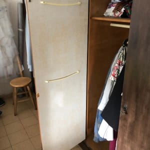 ארון עץ פתוח עם בגדים תלויים ומדף עליון