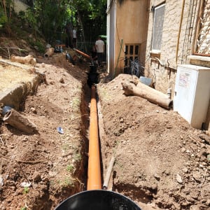 צינור כתום מונח בתעלה לצד בניין