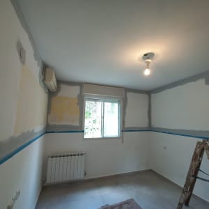 חדר עם קירות צבועים חלקית, סולם וצבע אפור