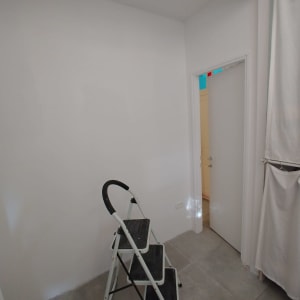 סולם קטן בחדר עם קירות לבנים ורצפת אריחים אפורה