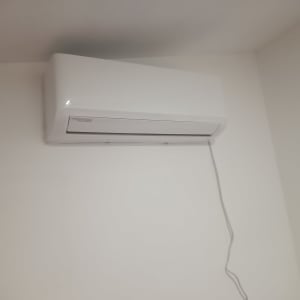 מזגן קיר לבן עם כבל חשמל תלוי