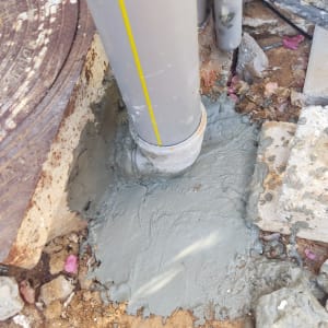 צינור פלסטיק אפור עם בטון סביבו באדמה