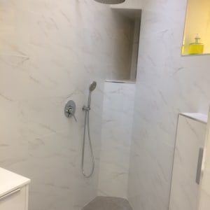 מקלחת עם אריחים לבנים וראש מקלחת עגול