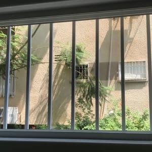 חלון זכוכית עם סורגים, נוף חיצוני של קיר