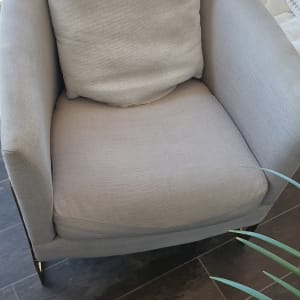 כורסה אפורה עם כרית על רצפת עץ כהה