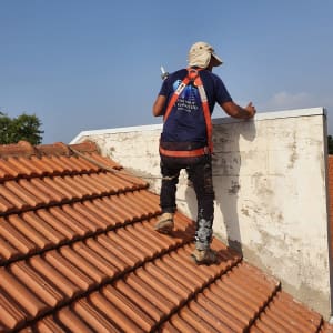 אדם על גג רעפים עם כלי עבודה ביד