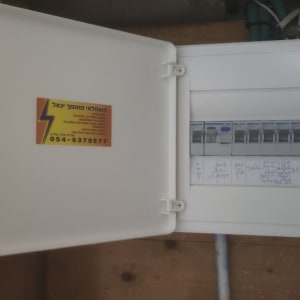לוח חשמל פתוח עם מפסקים ותווית חשמלאי