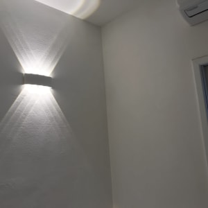 קיר פנים צבוע בלבן חלק עם גוף תאורת קיר דולק