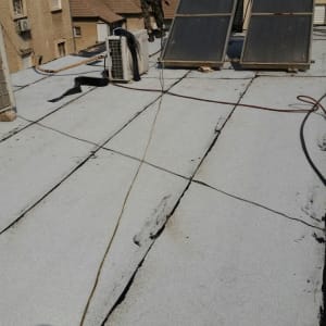 אדם על גג עם יריעות איטום וכלי עבודה