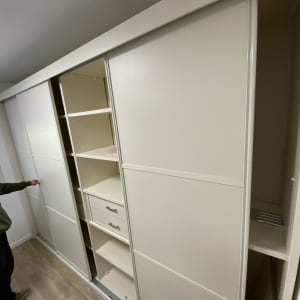 אדם פותח דלת ארון הזזה לבן עם מדפים ומגירות