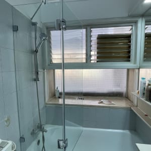 מקלחת עם דלת זכוכית, ראש מקלחת ומדף עם מוצרים