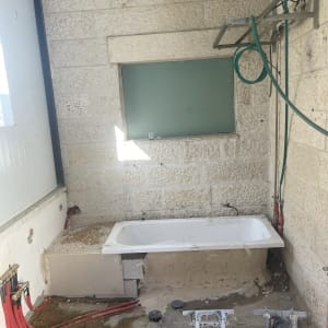 אמבטיה מותקנת עם צינורות אדומים, קיר אבן