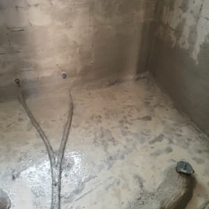 רצפת בטון רטובה עם צינורות חשופים בחדר שיפוצים