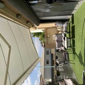 סוכך לבן פתוח מעל מרפסת עם דשא סינתטי