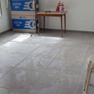 חדר עם אריחים חדשים, קרטונים וכלי ניקוי על שולחן
