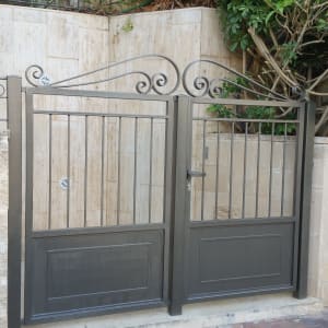 שער מתכת עם עיטורים על רקע קיר אבן