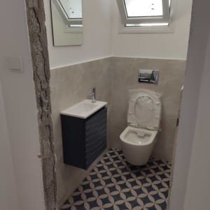 שירותים בשיפוץ עם קיר חשוף, כיור ואסלה