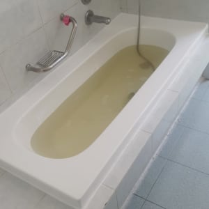 אמבטיה מלאה במים עכורים עם ברזים על הקיר