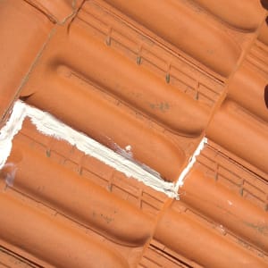 תיקון רעפים עם חומר איטום לבן על גג