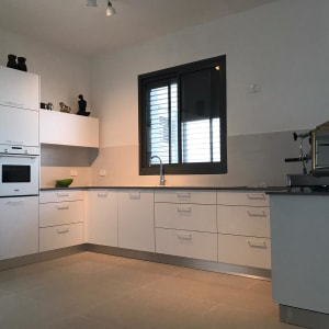 מטבח מודרני עם מקרר, תנור ומכונת קפה על השיש