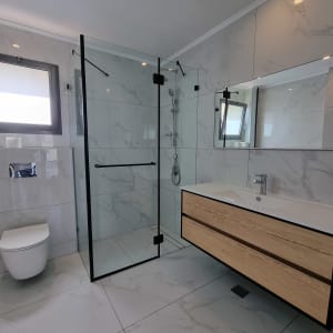 מקלחון זכוכית עם מסגרת שחורה בחדר אמבטיה מודרני