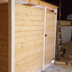 מחסן עץ עם דלת, סולם וכלי עבודה בחצר