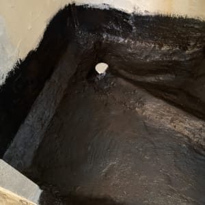 איטום רצפה עם חומר שחור סביב צינור ניקוז