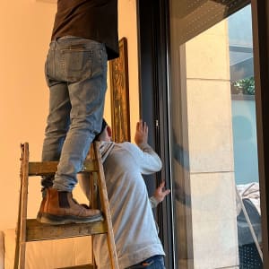 שני אנשים מתקינים מסגרת אלומיניום לחלון גדול