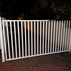 שער מתכת לבן עם סורגים אנכיים בחניה