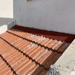 רעפים חומים על גג עם צינור ניקוז