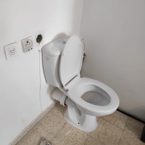 אסלה עם מכסה פתוח וכלי עבודה על הרצפה